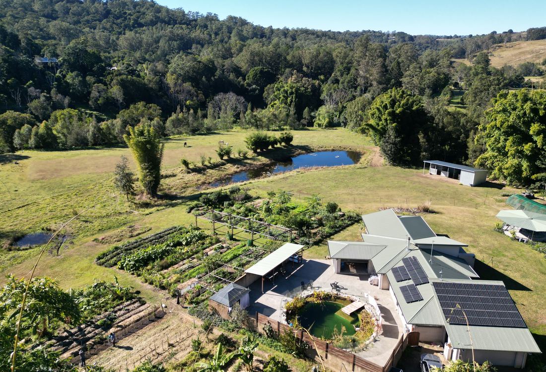 Aerial view of an off-grid homestead with solar roof, market garden and dam